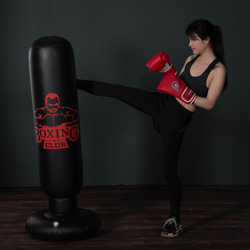 Woman using Sheila Merchandise free-standing kickboxing bag with red boxing gloves in workout gear