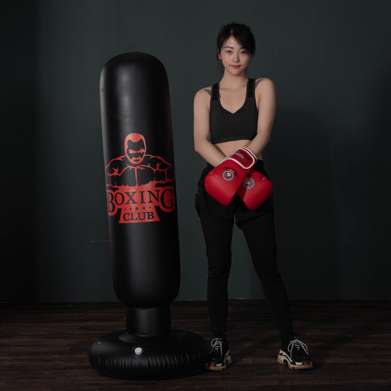 Free-standing kickboxing bag with boxing club logo next to woman wearing red boxing gloves