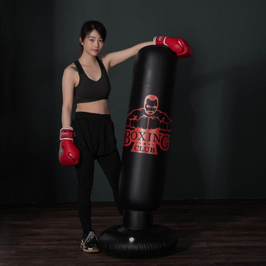 Young woman wearing red boxing gloves standing next to a free-standing kickboxing bag with Boxing Club logo