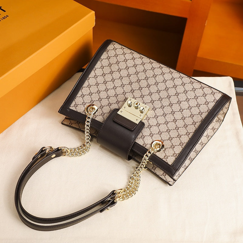 Stylish leather handbags with patterned fabric and black leather trim featuring gold chain straps on a white cloth