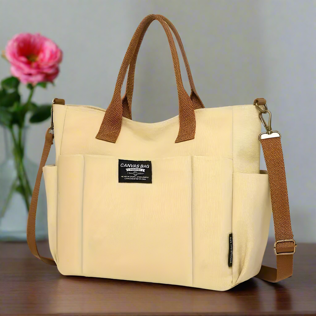 Beige multi pocket shoulder bag for women with brown handles and adjustable strap on wooden table