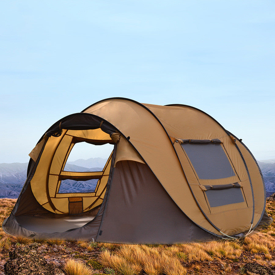 Outdoor automatic tent for 3-4 people in tan and gray set up on grassy terrain with mountain backdrop
