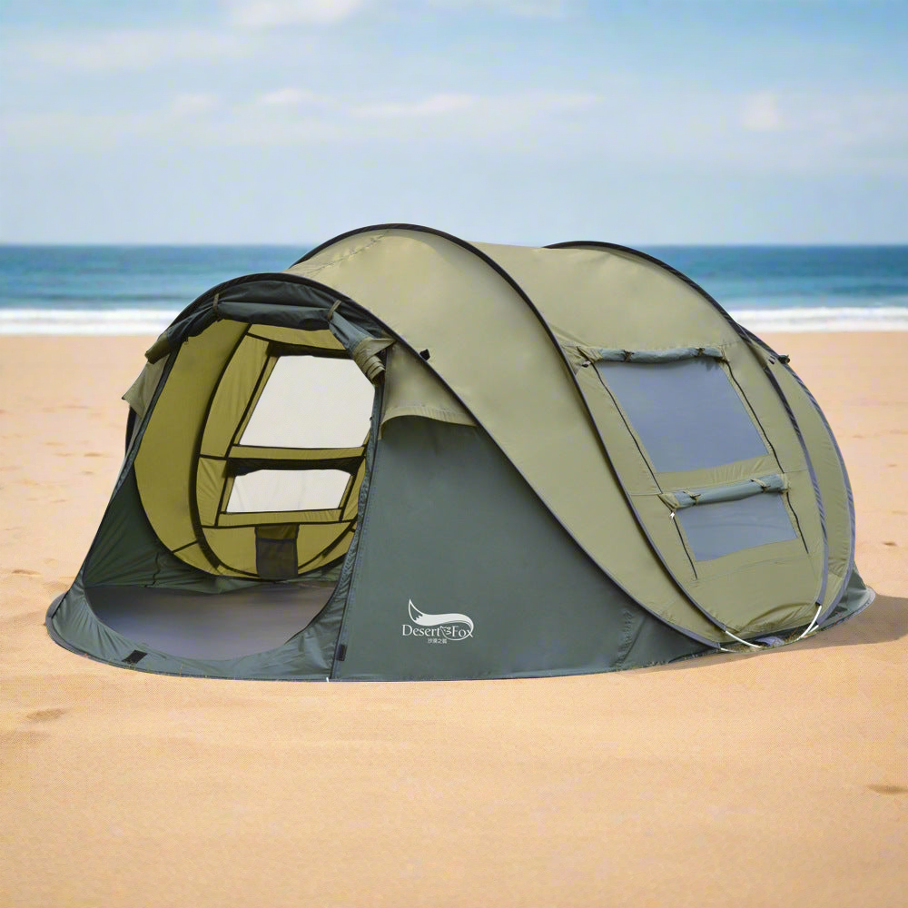 Outdoor automatic tent for 3-4 people in green set up on sandy beach with ocean background
