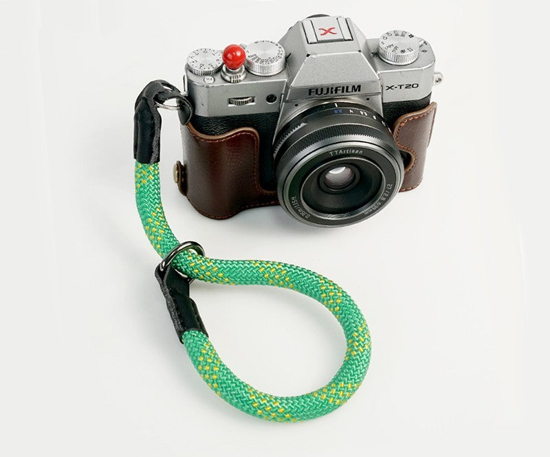 Durable camera wrist strap in green and yellow attached to silver Fujifilm X-T20 camera with leather case
