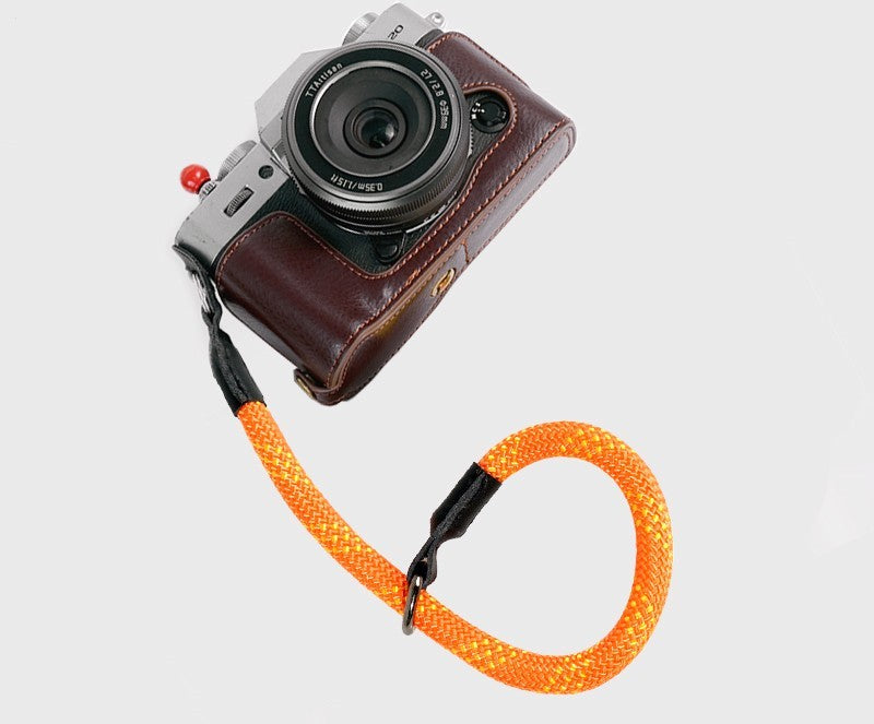 Sheila Merchandise resistant camera wrist strap in bright orange attached to a vintage-style camera for secure handling