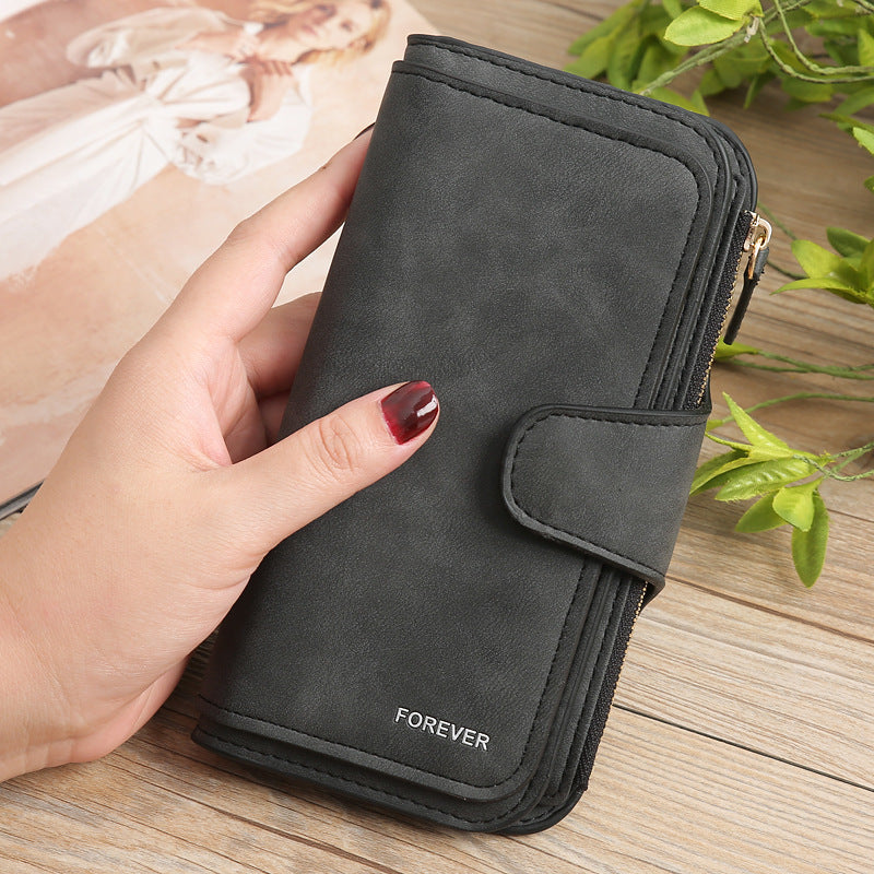 Matte PU leather multi function wallet for women in black held in hand with zipper and snap button