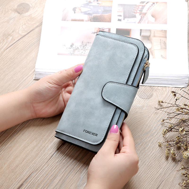Matte PU leather multi function wallet for women in light blue held by hands on wooden surface