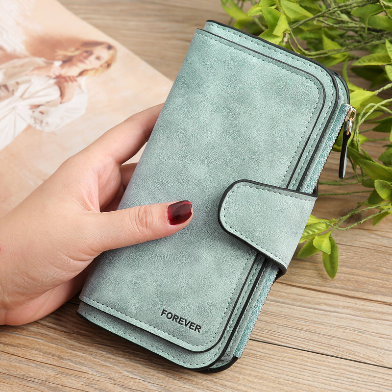 Matte PU leather multi function wallet for women in soft blue held in hand with zipper and snap closure
