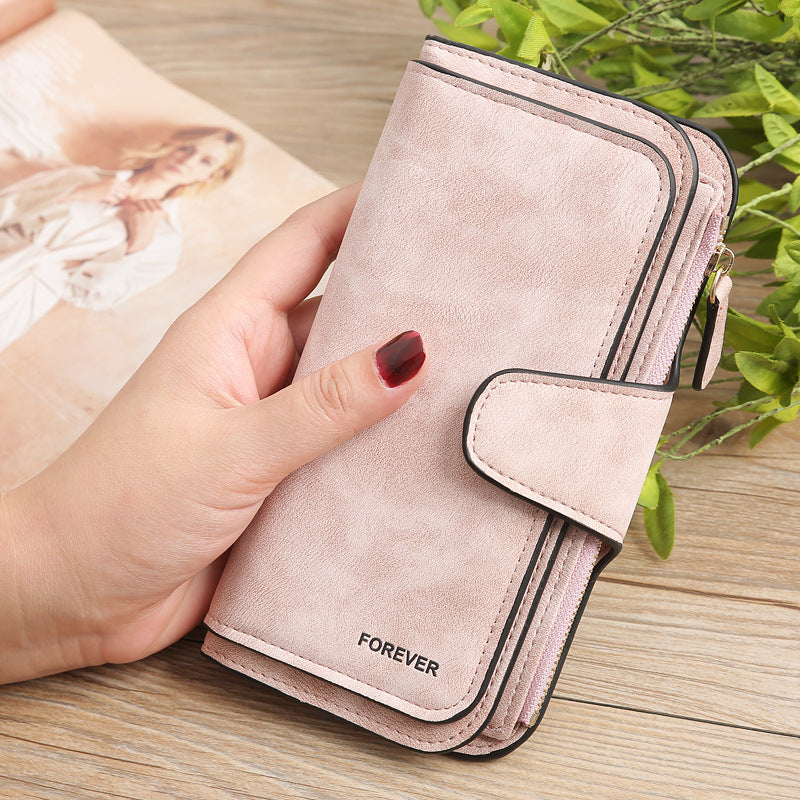 Matte PU leather multi function wallet for women in light pink color held in hand with snap closure