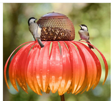 Petal shaped bird feeder in red with two small birds perched on its petals outdoors