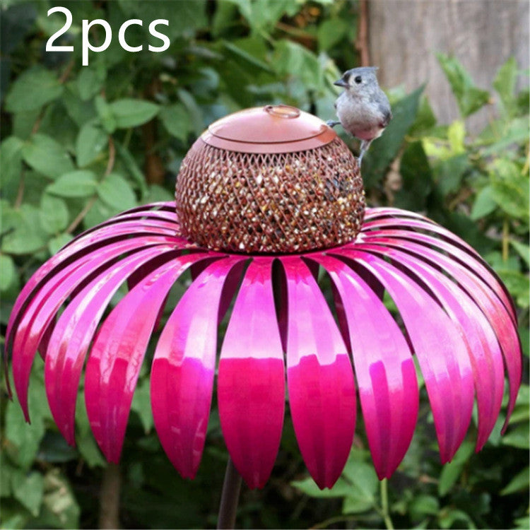 Pink petal shaped bird feeder with metal mesh center and small bird perched on top in garden
