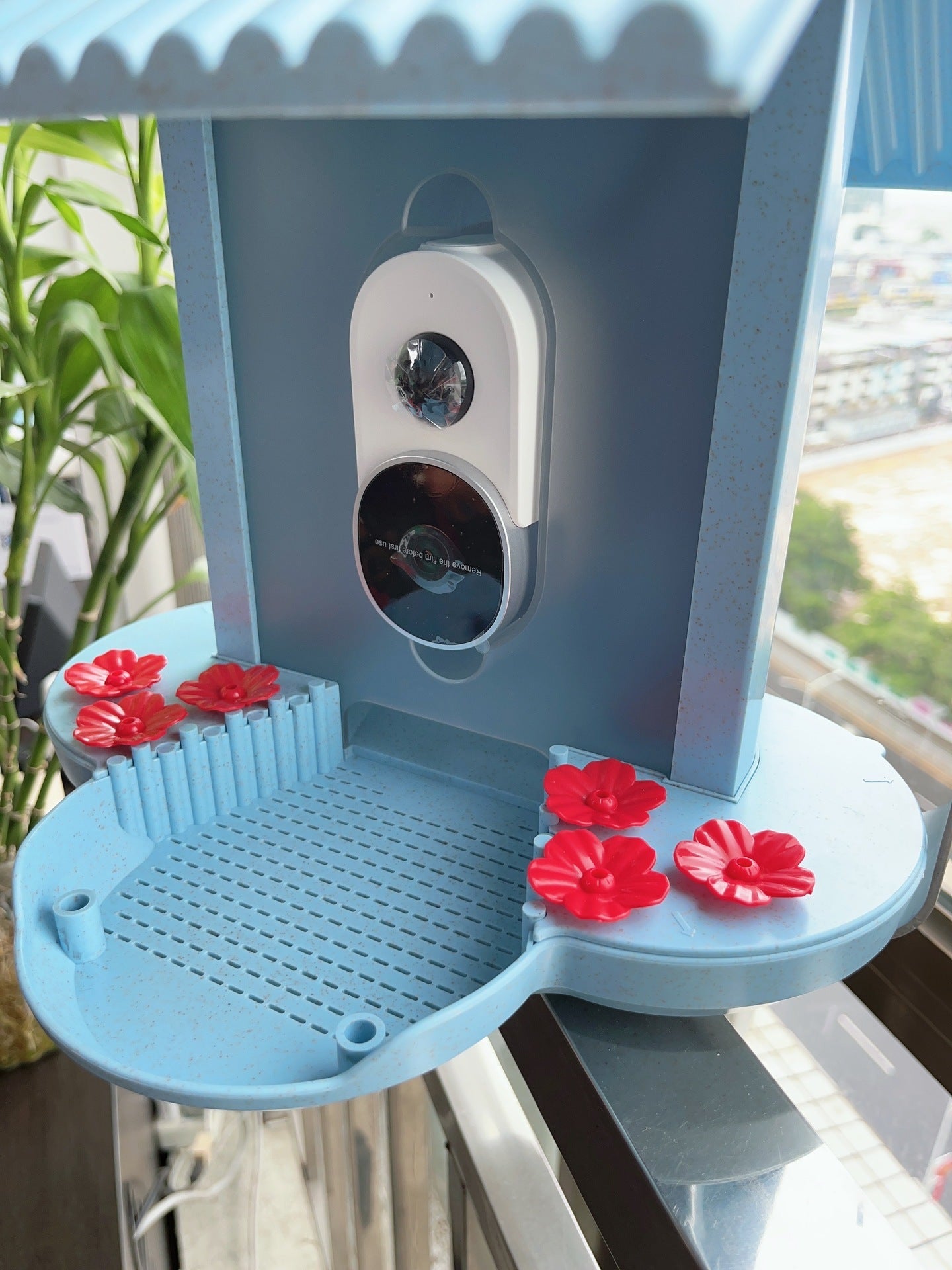 Smart hummingbird feeder in blue with red flower feeding ports and a camera for bird watching