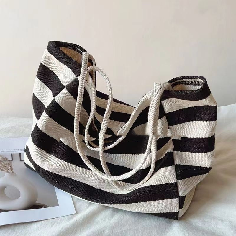 Striped canvas shoulder bag in black and white with double rope handles and artistic contrast design
