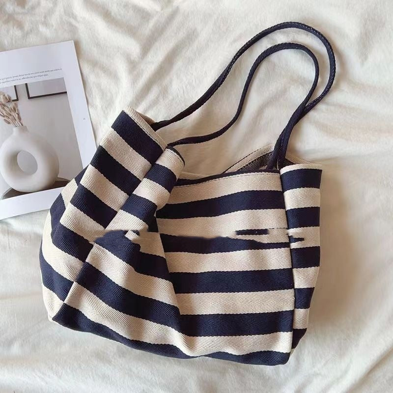 Striped canvas shoulder bag with bold black and beige horizontal stripes and double handles