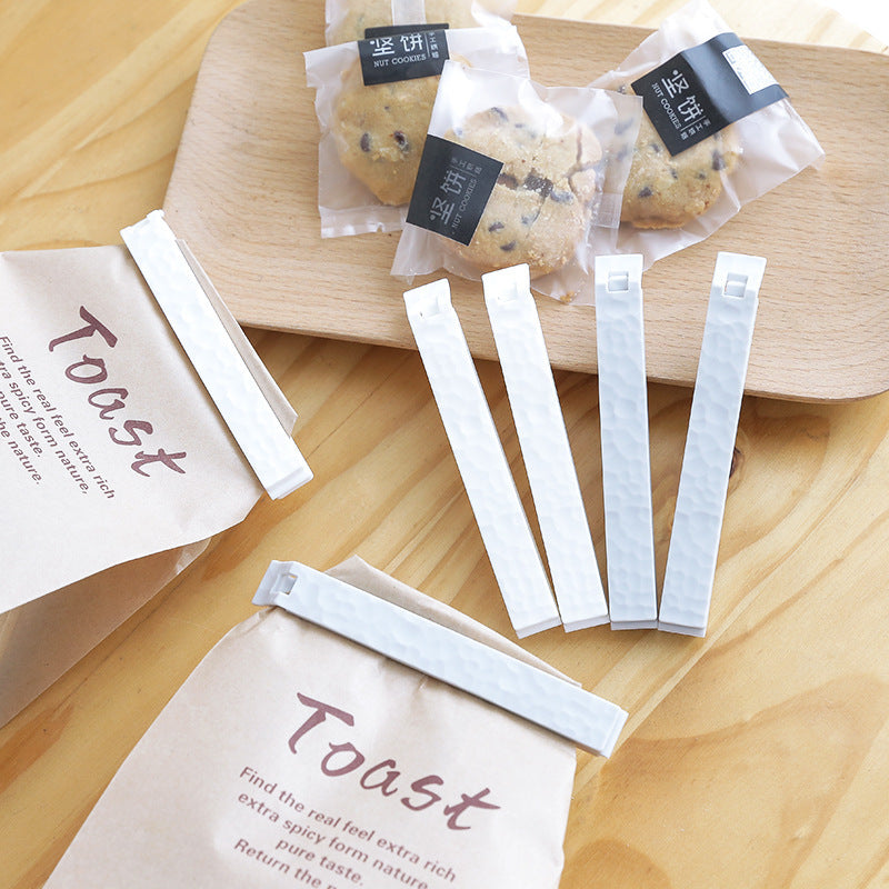 Sheila Merchandise reusable food sealing clips securing bread and cookie bags on a wooden surface