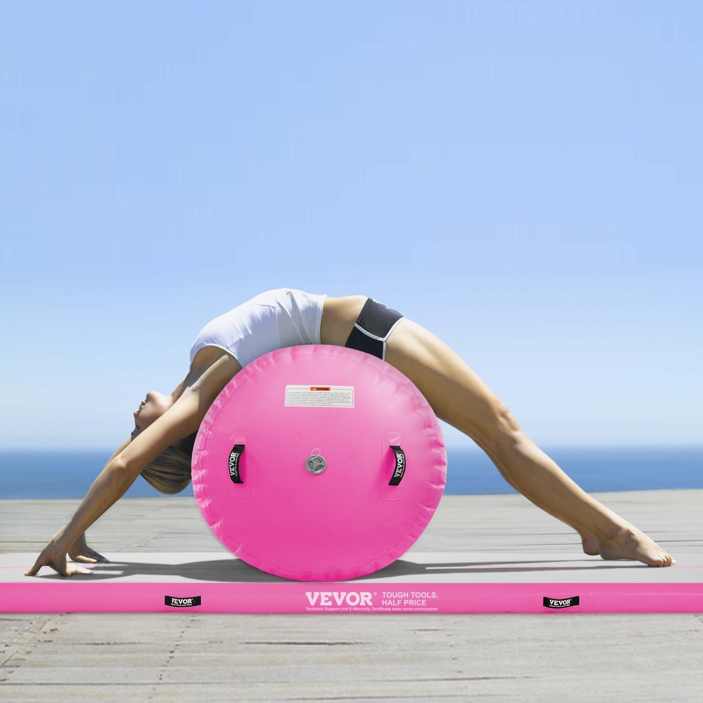 Inflatable gymnastics air mat set with pink mat and wheel used for backbend stretch on outdoor wooden deck