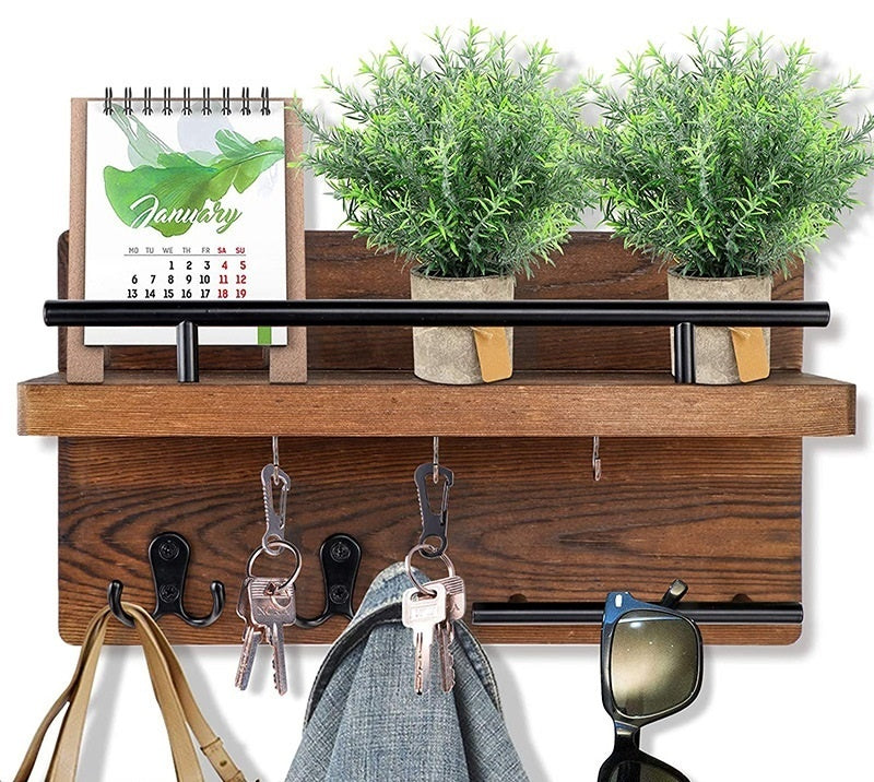 Sheila Merchandise wall-mounted wooden shelf with hooks holding keys, sunglasses, jacket, and decorative plants