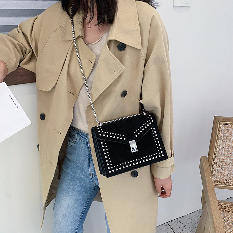 Woman wearing beige trench coat carrying women's red leather purse with chain over shoulder