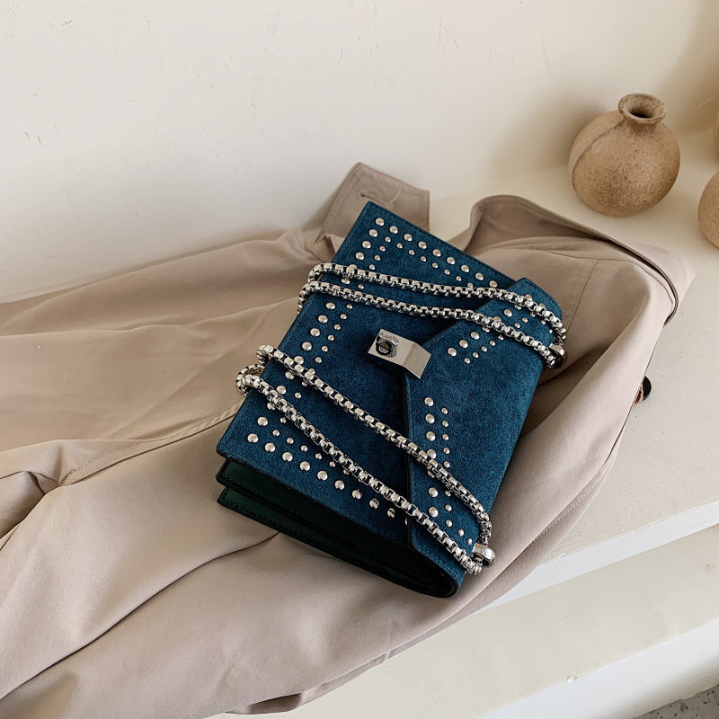 Women's red leather purse with chain by Sheila Merchandise placed on beige coat and white surface