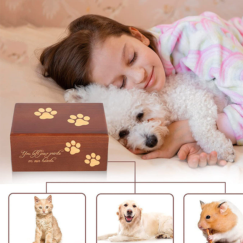 Wooden pet urn for ashes with paw print design and sentimental engraving beside girl hugging white dog