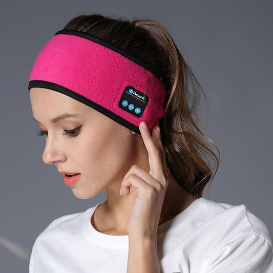 Sheila Merchandise Bluetooth fitness headband in pink worn by woman adjusting ear area