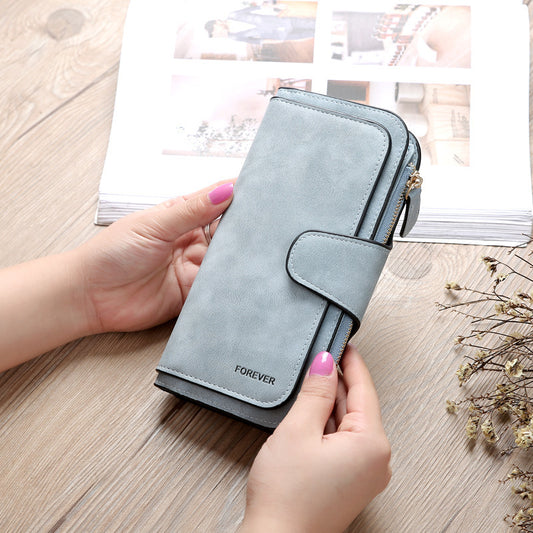 Matte PU leather multi function wallet for women in light blue held by hands on wooden surface