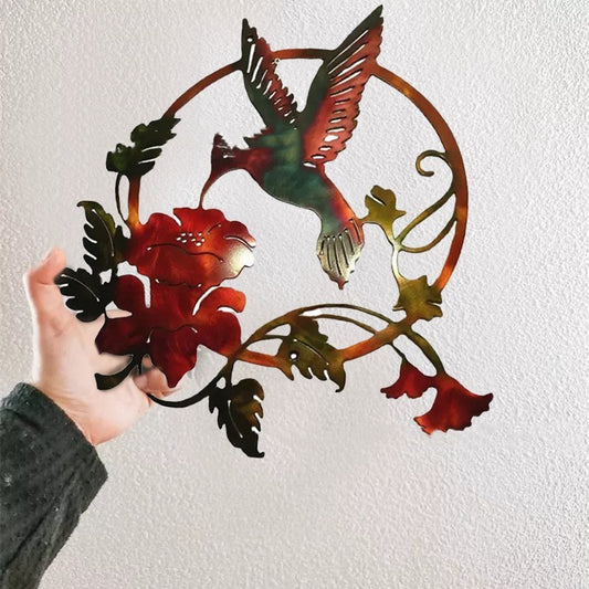 Hand holding Sheila Merchandise metal hummingbird wall art with red flower and green leaves design