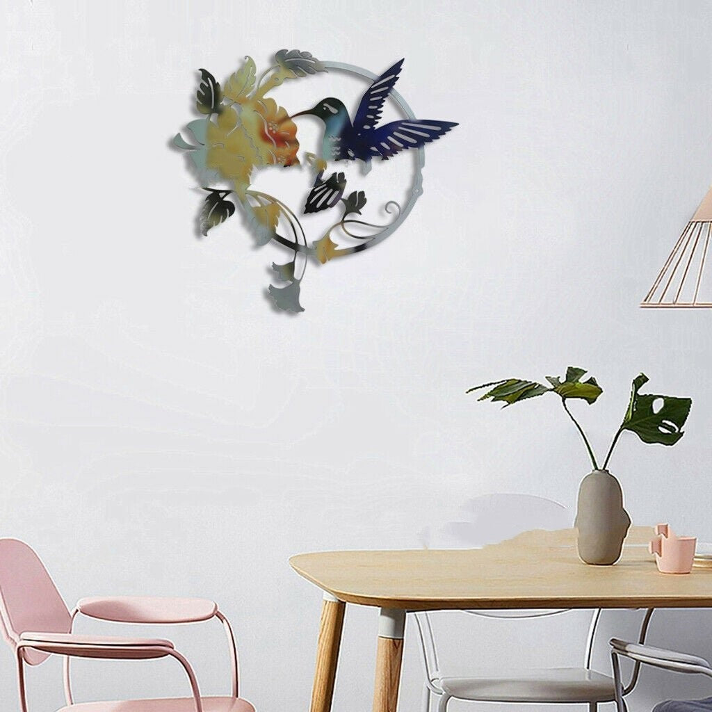 Sheila Merchandise metal hummingbird wall art featuring a colorful hummingbird and flower design hanging above a modern dining table