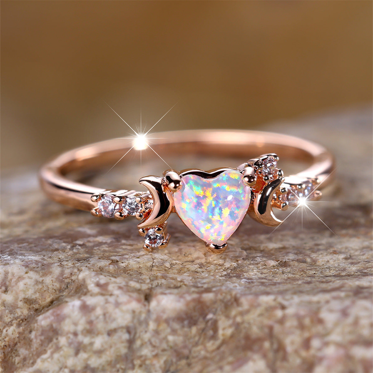 Rose gold moonstone love ring with heart-shaped gem and crescent moon details on stone surface