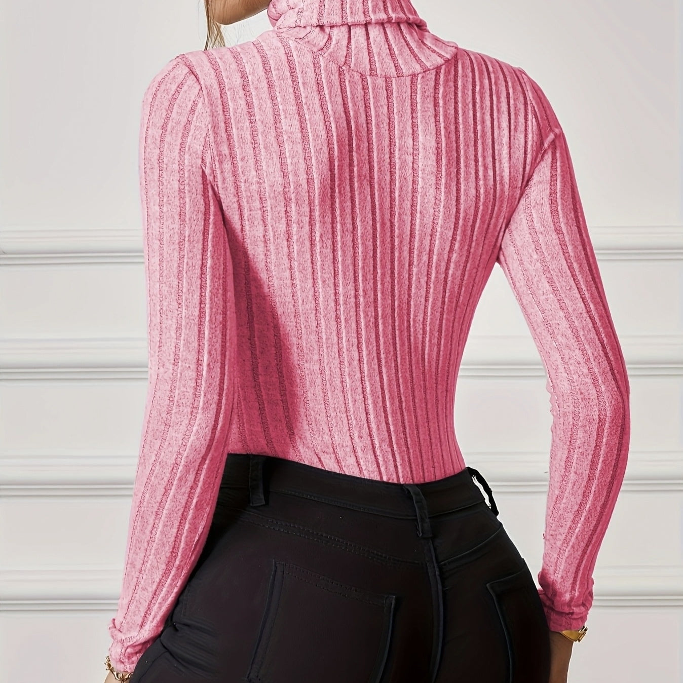 Back view of a woman wearing a pink turtleneck jumpsuit outfit with ribbed texture and long sleeves
