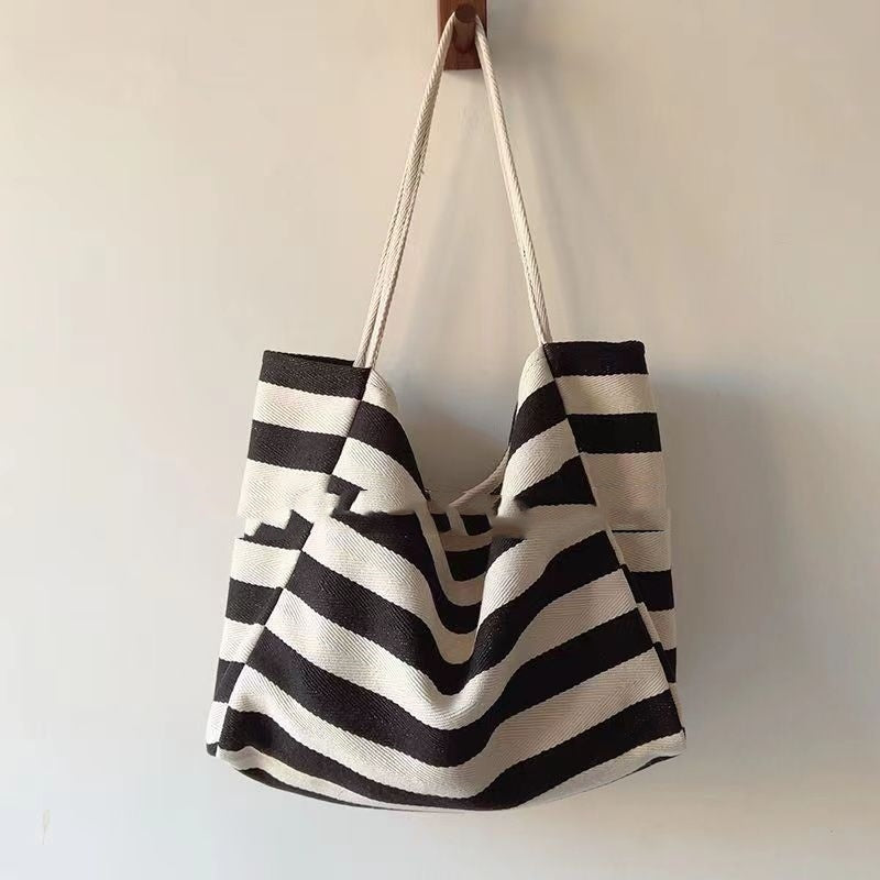 Striped canvas shoulder bag with black and white artistic contrast color stripes hanging on wall
