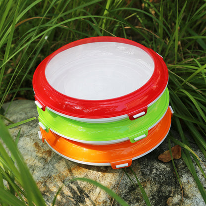 Stack of colorful food vacuum preservation trays with red, green, and orange lids placed outdoors on rock