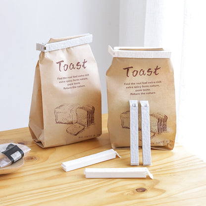 Reusable food sealing clips from Sheila Merchandise securing brown paper toast bags on wooden table