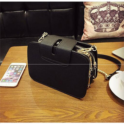 Black leather versatile fashion handbags with gold chain and zipper detail on wooden table