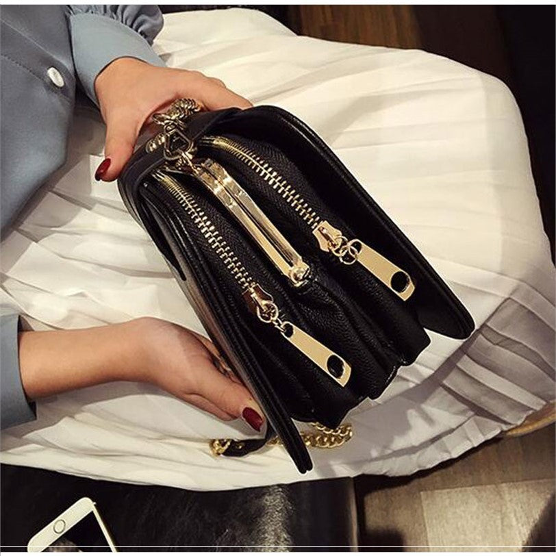 Black leather versatile fashion handbags with gold zippers and chain strap held by person with red nails