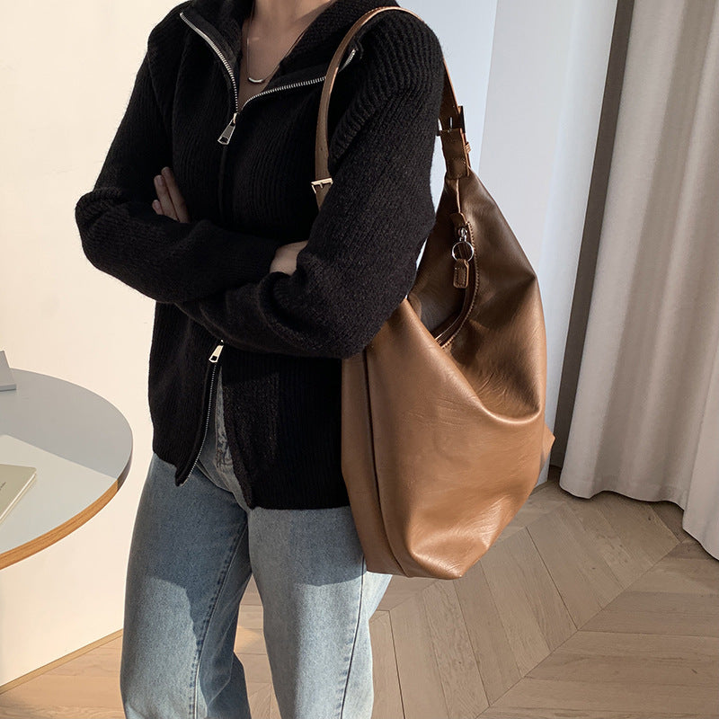 Versatile leather shoulder bag in brown soft leather worn over shoulder with casual outfit