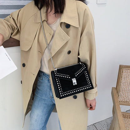 Woman wearing beige trench coat carrying women's red leather purse with chain over shoulder